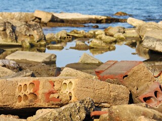 Ladrillos de una casa derruida en la orilla de una playa por efecto de la subida del nivel del mar
