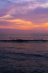 Surfers catch waves, surfing at sunset. Bali.