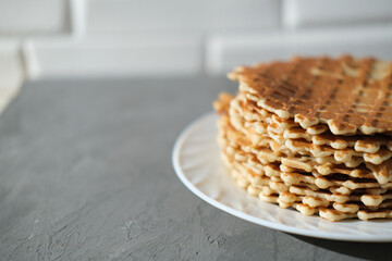Homemade Waffle Crisps in a stack on white plate. Thin dutch waffles on the kithen table, copy space. home baking concept.