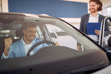Man in sales car salon sitting first time in new car
