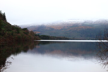 Gorgeous winter nature landscape wallpaper or screensaver of Killarney National Park, County Kerry, Ireland. Snow covered mountains reflected against a still Muckross Lake