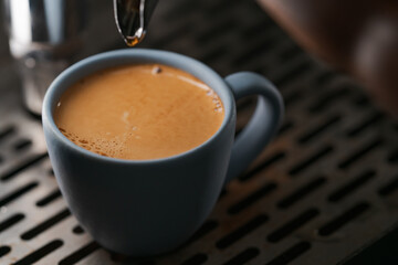 Closeup espresso last drop with single spout portafilter in blue cup