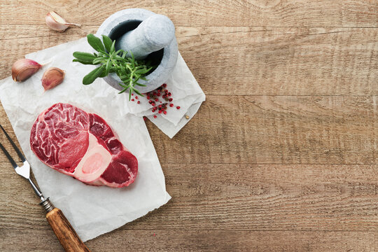 Osso Buco raw steak meat. Barbecue meat. Raw fresh cross cut veal shank and seasonings pepper, rosemary, thyme and salt on old wooden background. Beef Leg Slice with marrow. Italian menu. Top view.