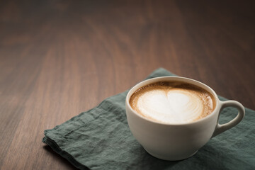 Fresh flat white with latte art in ceramic cup on wood table