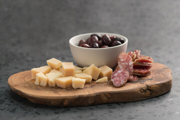 Italian antipasti with cheese olives and sausage on olive wood board