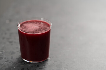 Glass of berry juice on concrete countertop with copy space