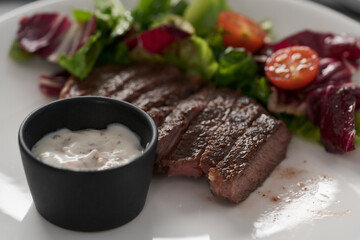ribeye steak with garlic sauce and fresh salad closeup