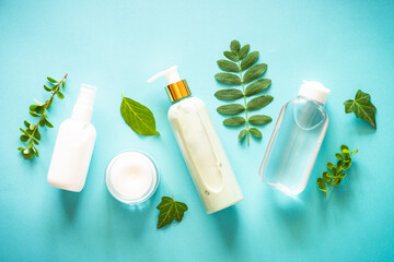 Fototapeta na wymiar Natural cosmetics concept. Skin care product, cream, serum, soap, mask with green leaves. Flat lay image on blue with space for your text.