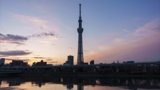 東京スカイツリーの側から昇る朝日のタイムラプス　朝焼けの空　隅田川