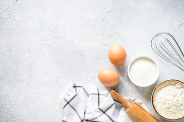 Baking background ingredients. Flour, sugar, eggs and others at light stone table. Top view with copy space.