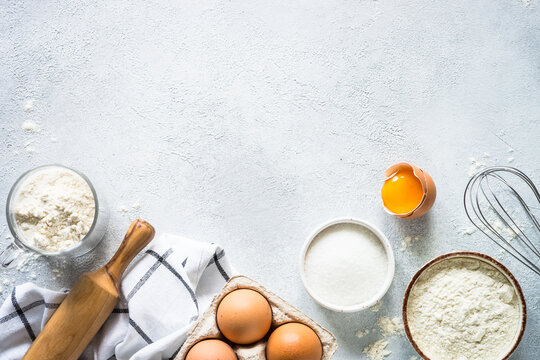Baking background ingredients. Flour, sugar, eggs and others at light stone table. Top view with copy space.