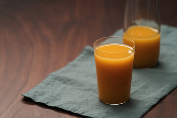 Fresh organic orange juice in tumbler glass on wood table
