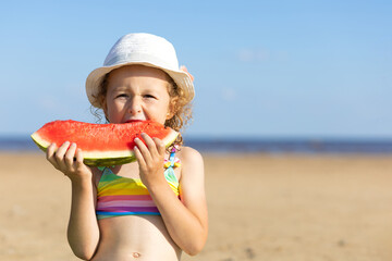 cute little girl eats ripe juicy red watermelon on the beach, coast, seashore. the concept of summer kid holidays, seasonal fruits and berries. copy space, text