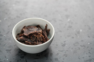 spiced beef jerky in white bowl on terrazzo countertop