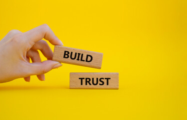 Build trust symbol. Wooden blocks with words Build trust. Beautiful yellow background. Businessman hand. Business and Build trust concept. Copy space.