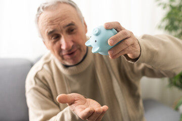 Senior caucasian man holding piggy bank with glasses depressed and worry for distress, crying angry...