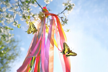 Floral wreath with colorful ribbons and butterflies on natural background. floral decor, Symbol of Beltane, Wiccan Celtic Holiday beginning of summer season. witchcraft, folk traditions, wicca rituals - obrazy, fototapety, plakaty
