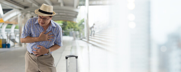 Asian elderly man having abdominal painful, tired, stressful while standing in corridor in city outdoor. Asian senior man standing alone and stomach ache while standing in corridor