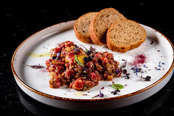 Raw beef meat tartar with sauce in plate