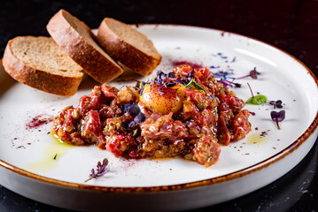 Raw beef meat tartar with sauce in plate