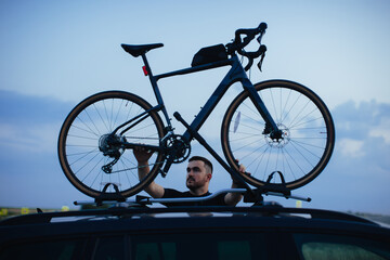 Fototapeta premium Male cyclist loading his bicycle on a rack of his car