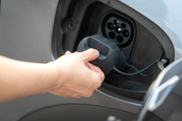 Human hand is opening the CCS DC charging socket's cover of the EV car, transportation action...