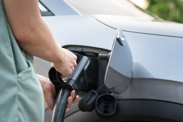 Action of person hand is plugging the CCS2 DC charger socket head with the EV car for recharging...