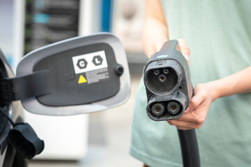 CCS2 DC charger socket head for charging the EV car is holded by human hand, ready for charging the...