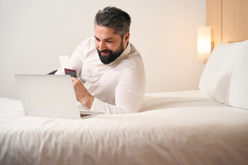 Joyous male entrepreneur using laptop in luxury suite