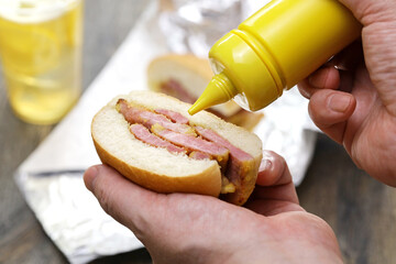 Putting mustard on a peameal bacon sandwich.　　Toronto's signature dish