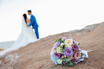 bellissimo bouquet in primo piano e sullo sfondo si vedono gli sposi felici 