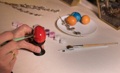 painting an egg red with a brush close-up
