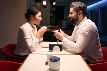 Romantic guy proposing to his beloved woman in coffee shop