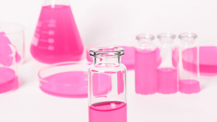 A flask, a jar for a laboratory with a pink liquid. Against the background of laboratory glassware. Petri dishes, flasks, test tubes. On a white, light background.