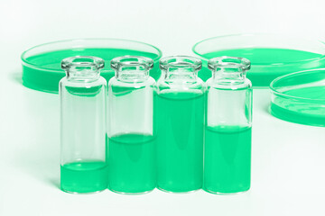 a set of flasks, jars for the laboratory with a green liquid. Against the background of laboratory glassware. Petri dishes, flasks, test tubes. On a white, light background.