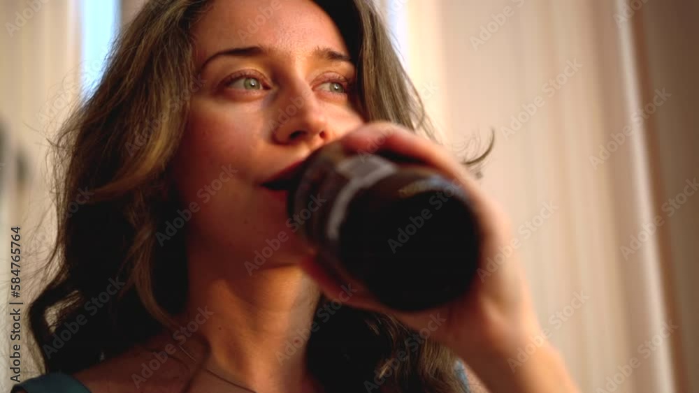 Wall mural Woman drinking bottle of kombucha green tea at home