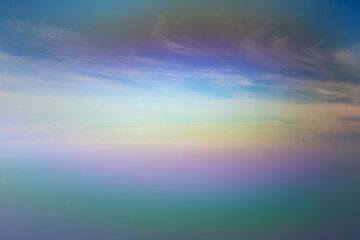 Blurred abstract rainbow background. White clouds on blue sky above the sea