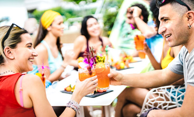 Happy people drinking cocktails at fancy pool party - Young friends having fun in luxury resort restaurant - Vacation life style concept with men and women enjoying drinks and fruit - Focus on glasses