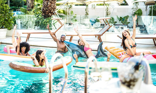 Young fancy people having fun at swimming pool party with lilo airbed and swim wear - Luxury life style concept with happy men and women enjoying summer day at exclusive resort - Bright azure filter