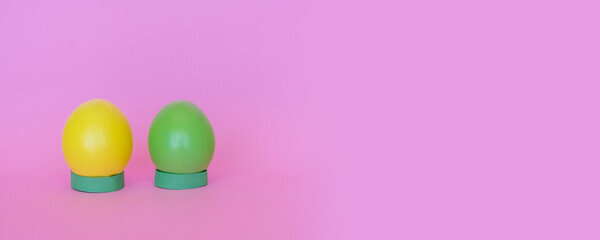 Easter eggs in a vertical position of yellow and green on a pink background.