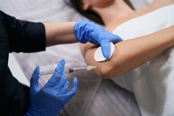 Medic doing injections in salon to beautiful woman