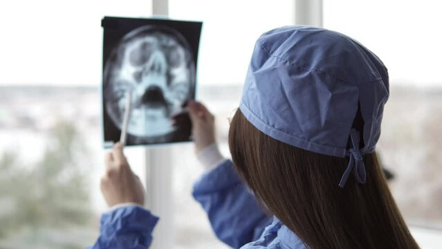 A doctor in a hospital room is examining an xray of the aftermath of an injury.