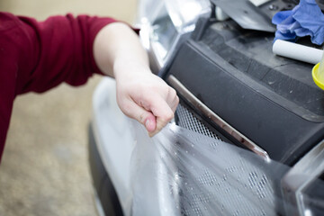 Installation of a protective film for car paint.The workers install a protective film on the car.