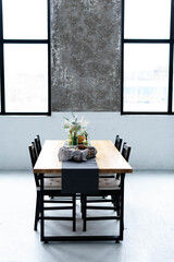 the kitchen table with chairs is decorated with a vase of flowers and a tablecloth near the large windows