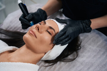 Beautician doing facial skin rejuvenation for beautiful client