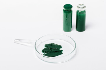 Spirulina mask or cream in a Petri dish. Cosmetic spatula. Spirulina powder in a jar. Spirulina oil or solution. On a white background.