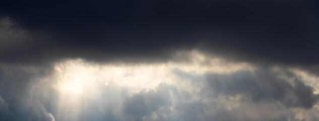 Sunlight penetrates the dark storm clouds