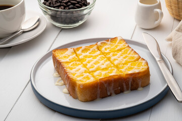 Grilled butter toast,golden brown crispy bread topped with sugar and sweetened condensed milk on white plate