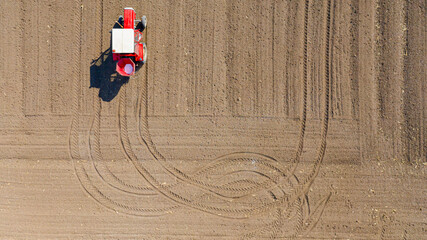 Aerial view on tractor as spread fertilizer over agricultural field