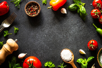 Food frame. Food cooking background on black stone table. Fresh vegetables, herbs and spices. Top view with copy space.